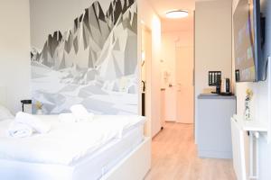 a bedroom with white beds and a wall with a mountain mural at stycoz - Modern studio - Central in Kempten +5 photos