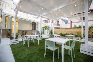 a patio with white tables and chairs and grass at Dimora Don Ciccillo B&B in Bagnara Calabra