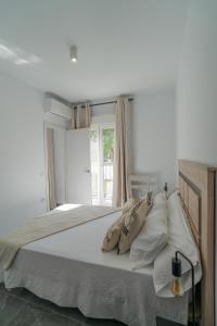 a bedroom with a large bed with white sheets and pillows at Apartamentos Áurea Casas del Sur in La Puebla de Cazalla