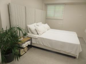 a bedroom with a bed with white sheets and a window at Gold House in Bet Shemesh