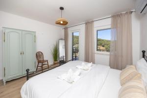 a white bedroom with a bed and a window at Rosa in Povlja