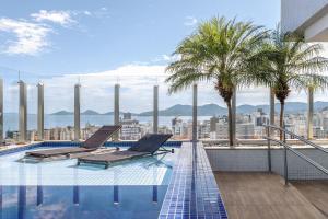 弗洛里亚诺波利斯Apto Centro Florianópolis Prox. Ponte Hercílio Luz的一座带两把躺椅的游泳池位于一座建筑的顶部