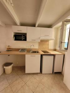 a kitchen with white cabinets and a sink and a microwave at Sanceflo in Mandelieu-La Napoule
