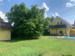 a yellow house with a tree next to a yard at Haus Matti in Meuro