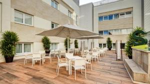 a patio with tables and chairs and an umbrella at Sercotel Coliseo in Bilbao