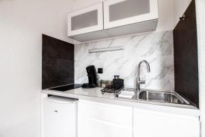 eine Küche mit weißen Schränken und einer Spüle in der Unterkunft Sweet-Thermal Amnéville loisir, parking gratuit in Amnéville