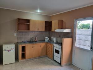 a kitchen with wooden cabinets and a white refrigerator at Las Lilas in Roque Pérez +7 photos