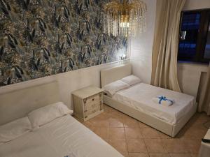 a room with two beds and a chandelier at Il Bacio di Roma in Infernetto