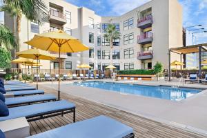 a pool at a hotel with chairs and umbrellas at Sleek & Central 2BR Apt Hollywood Hideaway in Los Angeles