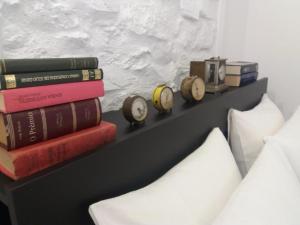 a shelf with books and clocks on it next to a bed at Casas de Alegrete - Castelo by Portus Alacer in Alegrete