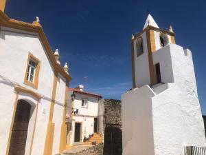 a white building with a clock tower on top of it at Casas de Alegrete - Castelo by Portus Alacer in Alegrete