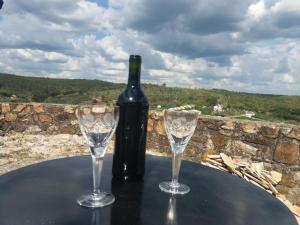 a bottle of wine sitting on a table with two glasses at Casas de Alegrete - Castelo by Portus Alacer in Alegrete