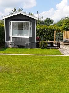 a small shed with a window in a yard at Chalet B2 in Westergeest +9 photos