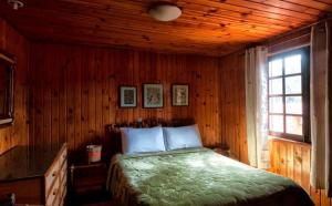 a bedroom with a bed in a wooden room at Pousada Bela vista Monte Verde in Monte Verde