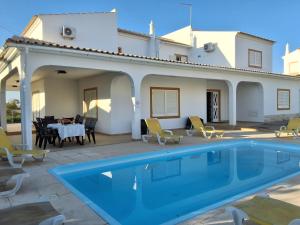 una villa con piscina frente a una casa en Villa Relax, en Bicas