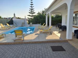 una piscina con sillas amarillas y un patio en Villa Relax, en Bicas