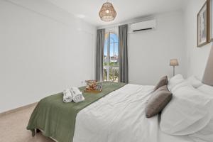 a white bedroom with a large bed and a window at Elegant Flat with Pool & Balcony by HostWise in Tavira