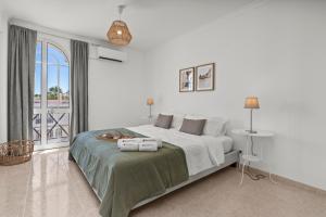 a white bedroom with a large bed and a window at Elegant Flat with Pool & Balcony by HostWise in Tavira