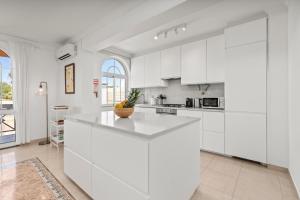 a white kitchen with white cabinets and a counter at Elegant Flat with Pool & Balcony by HostWise in Tavira