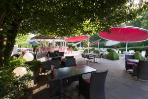 un patio con mesas, sillas y sombrillas rojas en Hôtel Bellevue en Porrentruy