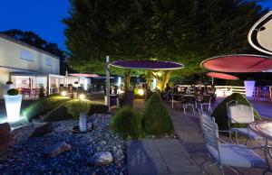 - une terrasse avec des tables, des chaises et des parasols la nuit dans l'établissement Hôtel Bellevue, à Porrentruy