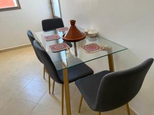 a glass dining room table with chairs and a vase on it at célestia in Sidi Ifni