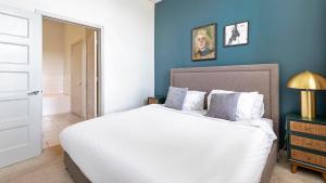 Un dormitorio con una cama blanca y una pared azul. en Downtown San Antonio Apartments by Landing, en San Antonio