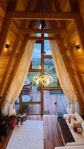 an attic room with a large window and a couch at Glamping Cabana Aysú in Córrego do Bom Jesus