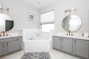 baño con 2 lavabos, bañera y espejos en Silver Lining - Luxury for 10, en Haines City