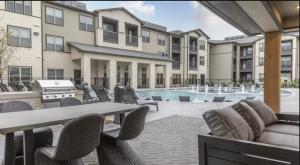 eine Terrasse mit Tisch und Stühlen und einem Pool in der Unterkunft Fairview Apartments by Landing in McKinney