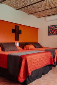 two beds in a room with a cross on the wall at Hotel Mesón de los Cristeros  +15 photos