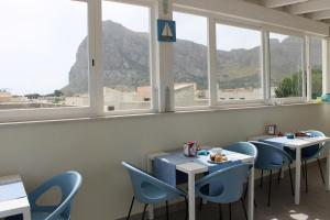 サン・ヴィート・ロ・カーポにあるPharosのテーブル2台と椅子、窓のあるレストラン