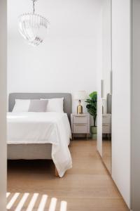 Habitación blanca con cama y lámpara de araña. en Stylish City Suite, Balcony, Augarten & Center, en Viena