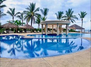 a swimming pool with a gazebo and palm trees at FRENTE AL MAR A PIE DE PLAYA ALBERCA y JACUZZI 7 in Mazatlán