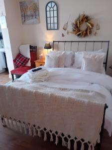 een groot bed met witte lakens en kussens bij Owls Roost in Stowmarket