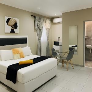 a bedroom with a white bed and a desk at U And I GuestHouse in Empangeni
