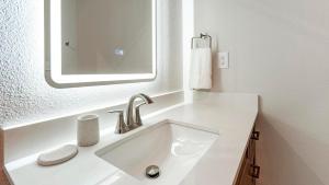 een witte badkamer met een wastafel en een spiegel bij Landing Apartments - Seguin in Seguin +42 foto's