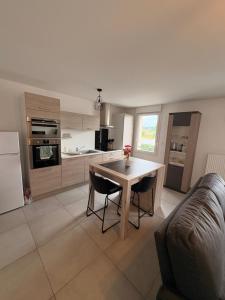 Una sala de estar con una mesa y una cocina. en Appartement 50m2 Amnéville avec balcon à 2 min des thermes, en Amnéville
