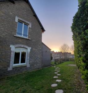 a brick house with a stone path in the yard at L'Évasion Maison typique de mineur in Flamanville