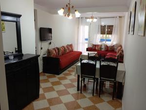 a living room with a table and a red couch at Arenabeach in Martil