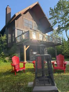 ラック・シュペリュールにあるChalet Inukshuk Luxury Log Cabin with Spa Lake View and Club Access near Mont Tremblantの赤い椅子2脚とグリルのあるツリーハウス