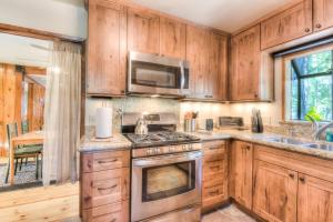 a kitchen with wooden cabinets and a stove top oven at Moonlight Cove w Grill Tahoe Beach Next Door in Tahoe Vista