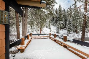 Un porche cubierto de nieve de una cabaña con árboles. en Joy on the River Stunning Waterfront Home for 10, en Olympic Valley