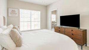 a bedroom with a white bed and a flat screen tv at Landing at Settlers Ranch - Pasadena in Houston