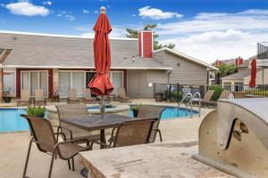 a patio with a table and a red umbrella at Landing at Quail Ridge - Grand Prairie in Grand Prairie