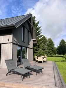 a deck with chairs and a table and a building at Bernātu Kalnmaļi in Bernāti