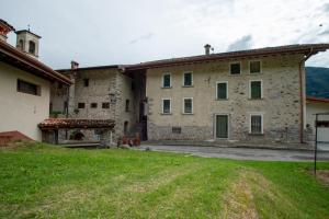 Le Cornici Home Suites - Apartments - Lake Idro في Ponte Caffaro: اطلالة خارجية على بيت حجري كبير مع ساحة