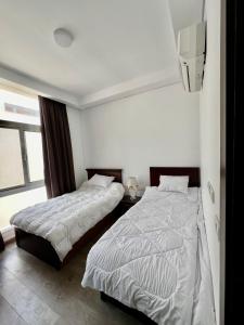 エル・アラメインにあるModern Furnished Apartment Mazarine North Coastのベッドが2つと壁にテレビがある寝室