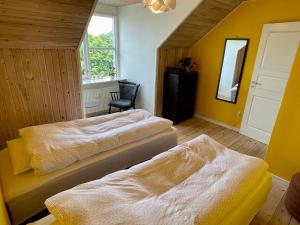 a bedroom with two beds and a chair and a mirror at Silkeby Bed & Breakfast in Silkeborg +26 photos
