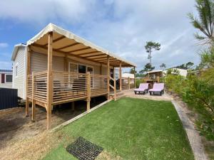 a house with a deck and a grass yard at Mobil home Cap ferret les viviers siblu in Lège-Cap-Ferret